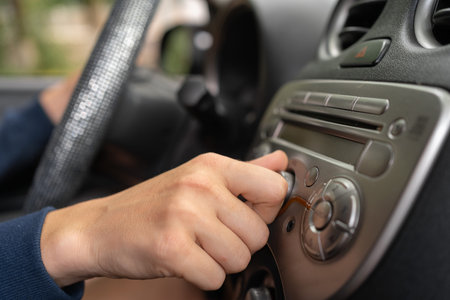 Woman turning button on car radio for listening to music. Transportation and vehicle