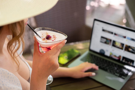 Young woman in summer using laptop looking at computer screen enjoying watching funny social media video, sunny day. Blurred backgroundの写真素材