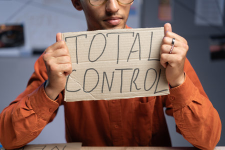 Conspiracy and a man sits and holds a inscription - total control in his hands. Conspiracy theorist and fake news. Politics and conspiracy theory.の写真素材