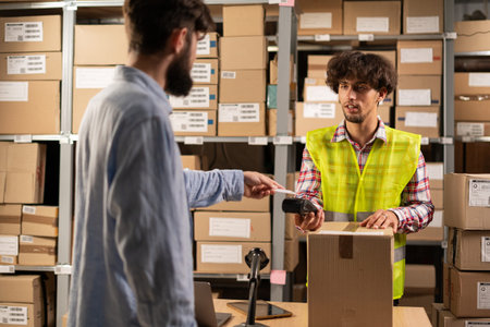 Male customer payment online order at pick-up point. Online store warehouse arabic worker giving...