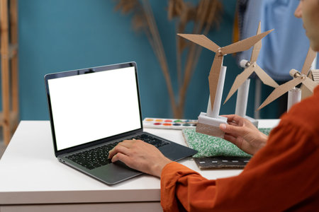 Young woman architect, working on an ecological construction project in her home office using laptop...