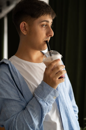 Men drink pearl milk tea through a straws looking away, close-up.