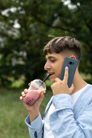 Young woman calling on smartphone and drink bubble tea on streetの写真素材
