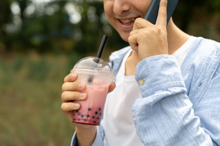 Young woman calling on smartphone and drink bubble tea on street. Copy spaceの写真素材