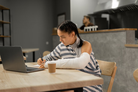 Young woman freelancer hold a pencil taking notes and drinking coffee at the cafe.の写真素材