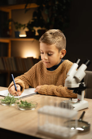 Young scientist doing some experiments with microscope at home. Preschool boy conduct science...