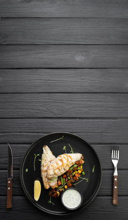 Grilled BBQ fish fillet with cooked vegetables on dark background, top viewの写真素材