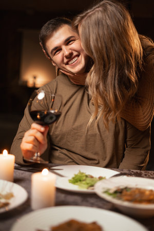 romantic dinner for two, married couple at the table with wine. Woman kisses a man. The concept of celebrating valentines day, birthdayの写真素材