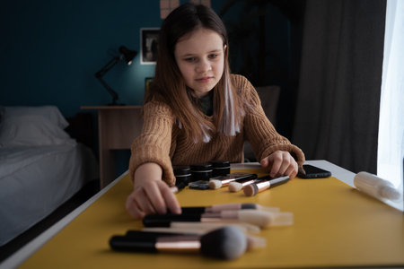 Child photographer lays out cosmetics and makeup brushes on the table preparing for shooting at home