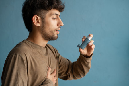 Young arabic man suffering from asthma attack, using nebulizer on room backgroundの写真素材