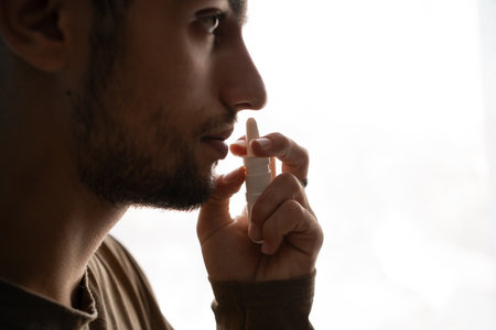 Young arabic man using nasal spray on white backgroundの写真素材