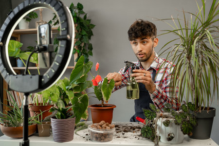 Online influencer guy in social media marketing live blog hobby. Arabic man planting plant into new pot and recording videoの写真素材