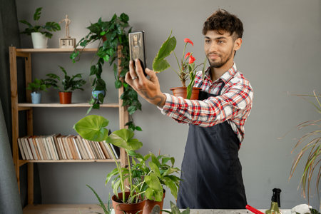 Arabic male gardener or florist portrait take care and cultivate domestic flowers plants. Home gardening conceptの写真素材