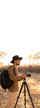 Young photographer wear hat taking pictures of the beautiful moments during the sunsetの写真素材