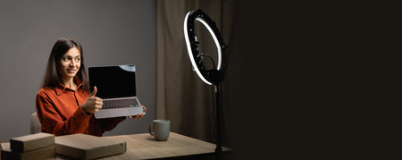 Hispanic female blogger unboxing parcel with laptop computer on smartphone camera, recording video...