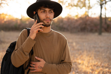 Freedom, happiness, travel and vacations concept. Arabic male tourist in hat use smart phone over nature backgroundの写真素材