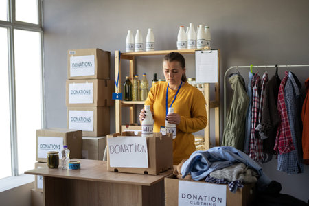 Woman working in charitable foundation. Volunteer packing donation box. Female volunteer sort...