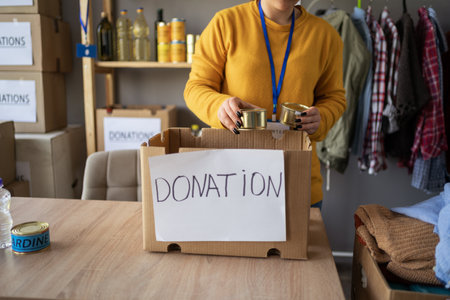 Volunteer packing food in boxes at refugee assistance center. charity, donation and volunteering conceptの写真素材