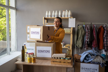 Happy smiling female volunteer with food in box at distribution or refugee assistance center....