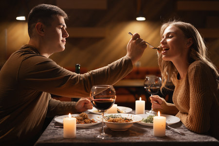 Romantic Relationship. Couple in love have dinner in cafe. Smiling man is feeding his woman. Celebrating Valentines Dayの写真素材