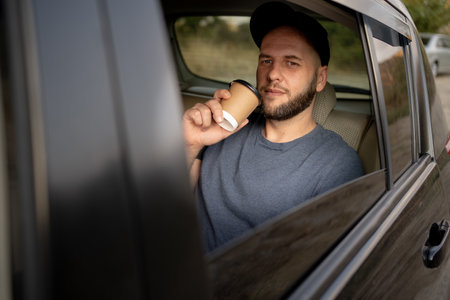 Happy bearded man passenger drinking takeaway coffee in taxi car. Transport, vehicle and people conceptの写真素材