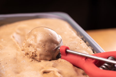Ice cream is scooped from the container with a special scoop.の写真素材