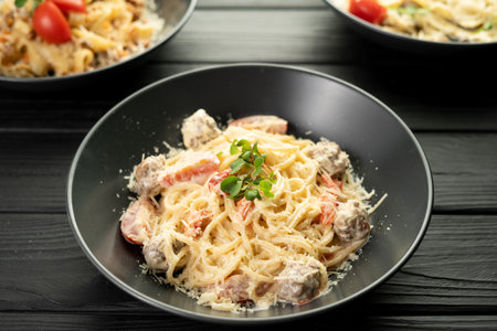 Spaghetti pasta with meatballs in creamy sauce with Parmesan cheese on a dark wooden background. Restaurant menuの写真素材
