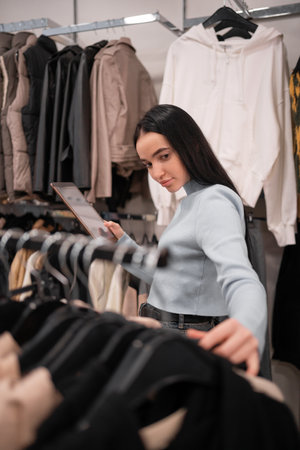 Female shop owner conducting a quality control check in her clothing boutique using her digital tablet. Business Lady inspecting garment into her clothes shopの写真素材