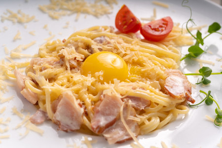 Traditional Italian pasta or spaghetti carbonara with yolk, parmesan cheese, bacon on white plate, top view.の写真素材