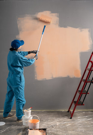 Rear view of a woman painter painting a wall with a paint brush. Home renovation concept.の写真素材