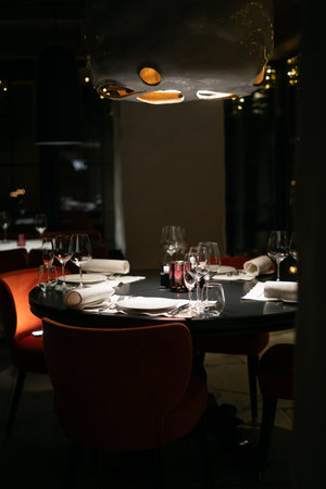 Served dinner table in a restaurant. Table banquet ready for guests, empty plates, glasses, forks and napkins. Restaurant interiorの写真素材