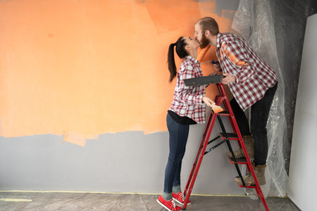 Happy lovers couple are repair in renovation, improvement of room and kissing preparing to move to...