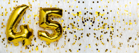 Golden foil balloon number, figure forty-five on white with confetti background. 45th birthday card....