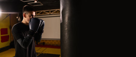 Young sportsman training boxing in the punching bag. Sport, self defense, boxing and training conceptの写真素材