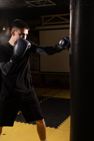 Full length view of young male boxer training with punching bag in he gymの写真素材