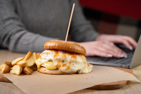 fast food on workplace. burger near laptop. lunch break.の写真素材