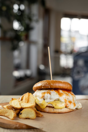 Tasty big American burger with beef meat, burner cheese and sauce. Cheeseburger served on wooden board in restaurant. American fast food lunchの写真素材