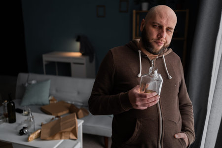 Depressed lonely man drinking whiskey at home. Alcoholism, alcohol addiction and people