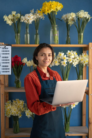 Portrait of Smiling Woman Florist small business flower shop owner. Lady using laptop to take orders...