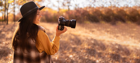 Young female photographer taking picture of Nature in Autumn forest