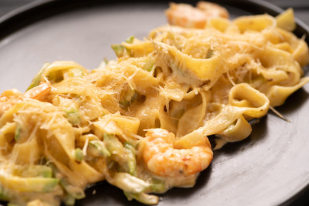 Italian pasta fettuccine with shrimps in a creamy sauce with parmesan cheese on black plate, close-up. top viewの写真素材