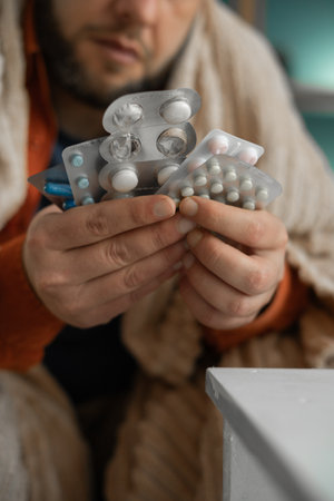 Close-up of sick man hands hold pack of different tablet blisters at home. Panacea, life save, prescribe medicament, disease healingの写真素材