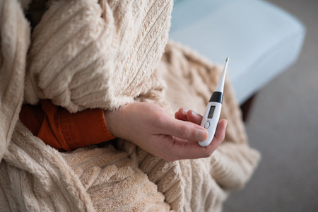 Close-up shot of a man looking at thermometer. Male hands holding a digital thermometer after measures the temperature. focus on thermometer.の写真素材