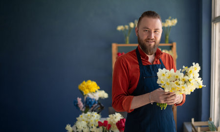 A florist creating a beautiful bouquet of spring daffodil flowers works in his flower shop. Small business ownerの写真素材