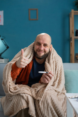 Happy man with a thermometer in his hands recovery, victory over the disease