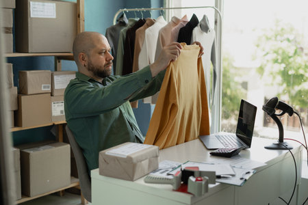 Online shopping business concept, male entrepreneur checks order on laptop and checks whether it is the dress. Small business.の写真素材