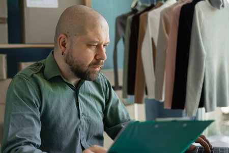 Small business startup man using laptop and boxes to receive and check online orders to prepare...