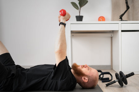 athletic man exercises with dumbbells lying on fitness mat at home. Sport, healthy lifestyle.