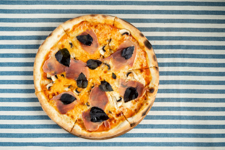 Delicious fresh pizza with jamon bacon and purple basil served on the table in a pizzeria. Italian pizza conceptの写真素材