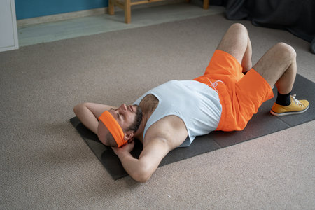 After his workout, a man in colorful athletic attire is resting on his exercise mat